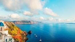 View of ocean, coastline, 和 blue-roofed buildings in Greece