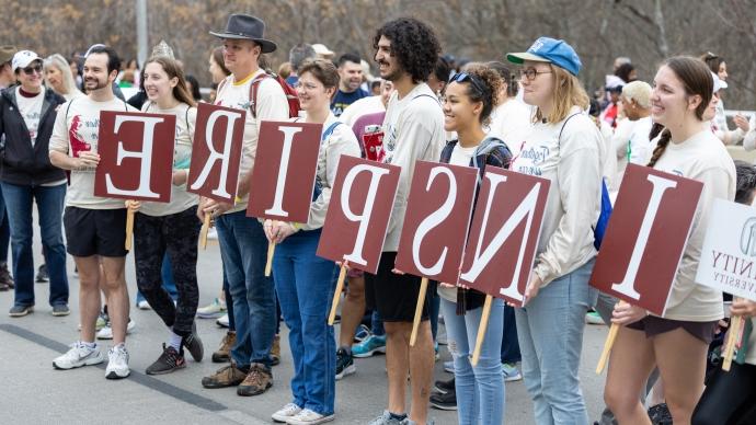 Seven members of the Trinity community line up with signs that spell INSPIRE