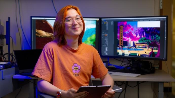 A student with orange hair 和 clothes sits in front of a computer.