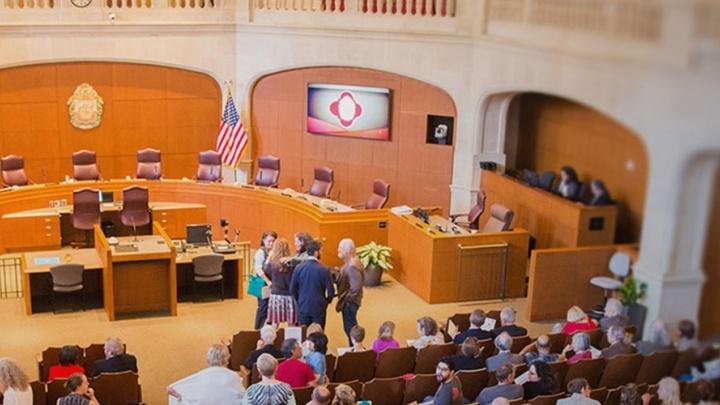 政府 officials and community members gather together in council room for a hearing.