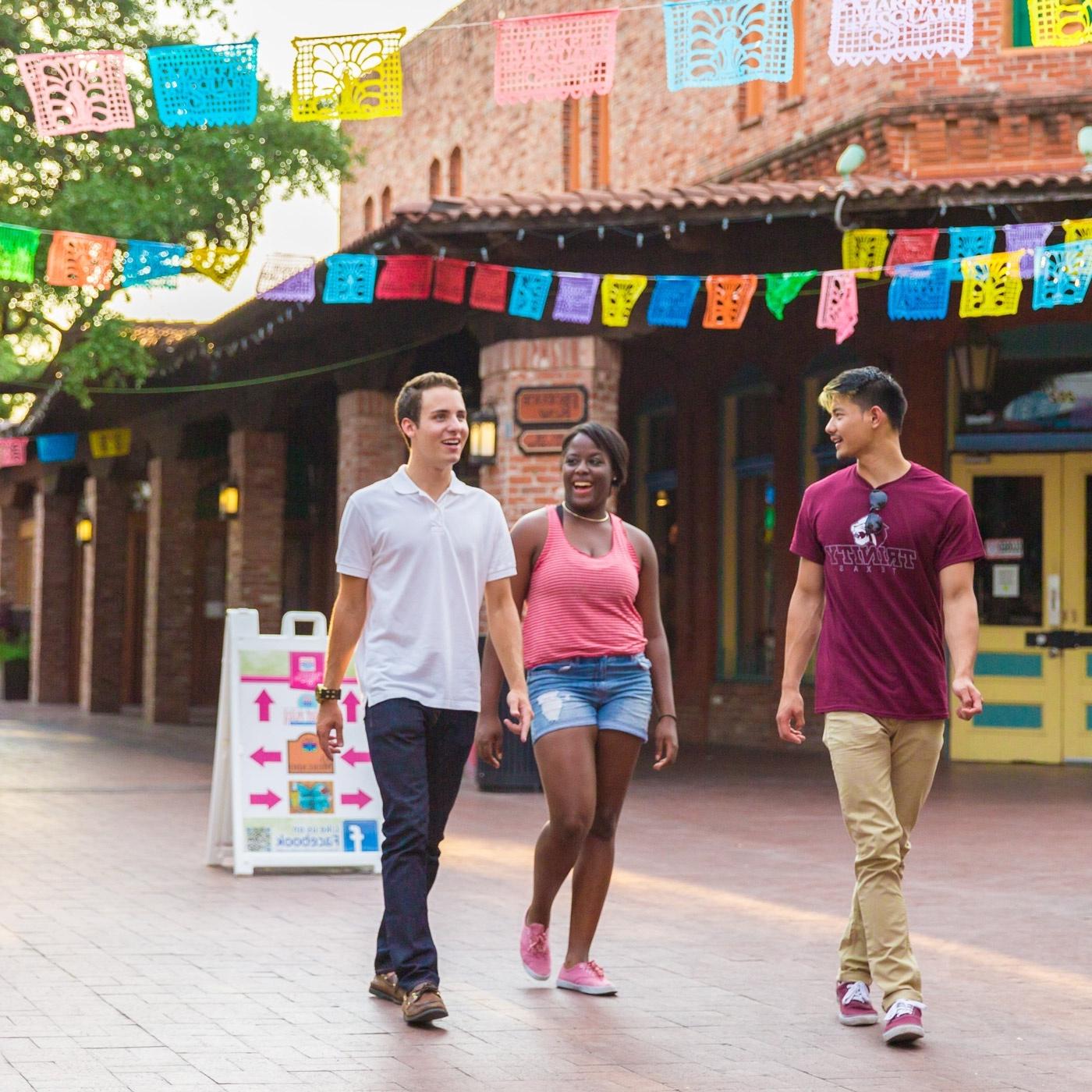 three 赌博娱乐平台网址大全 students walk through Market Square under papel picado