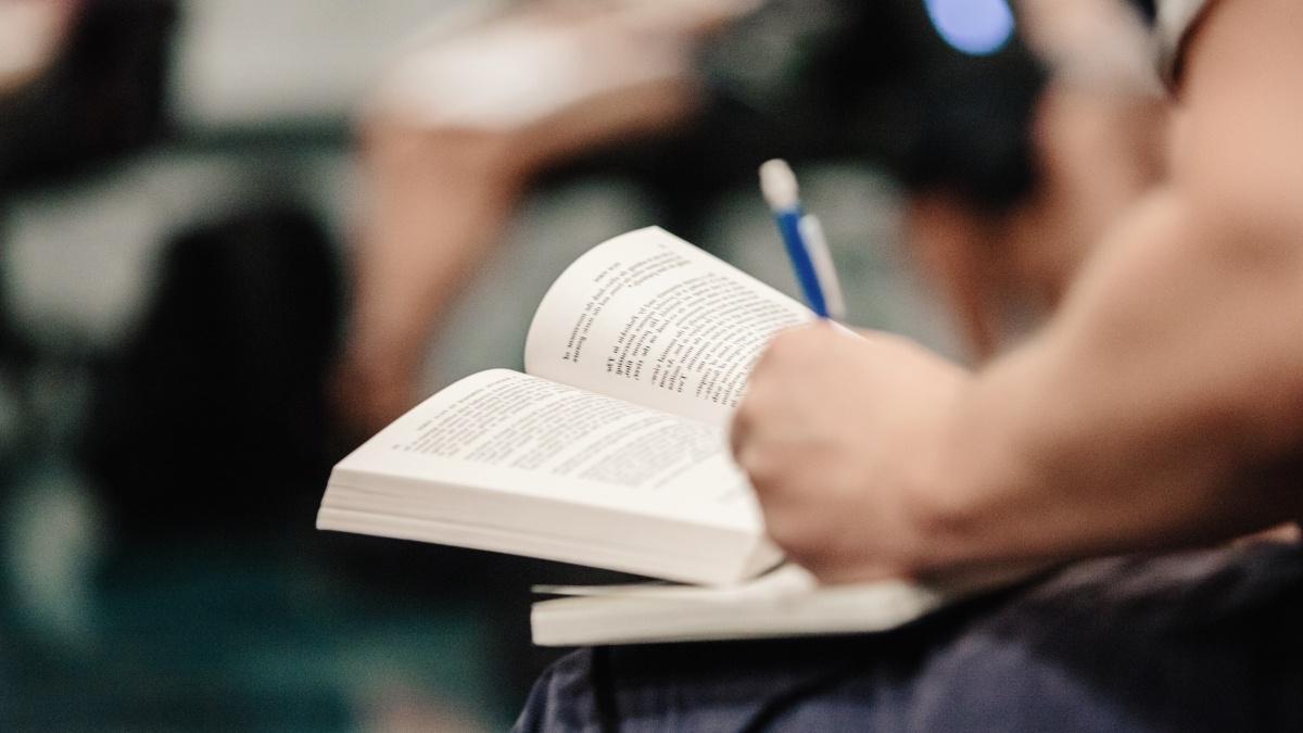 A student writes notes in an open book