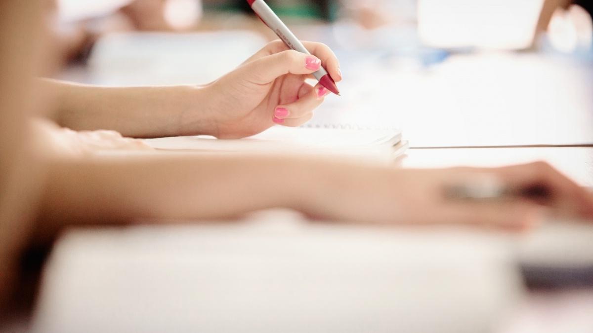 Close up of people writing in notebooks