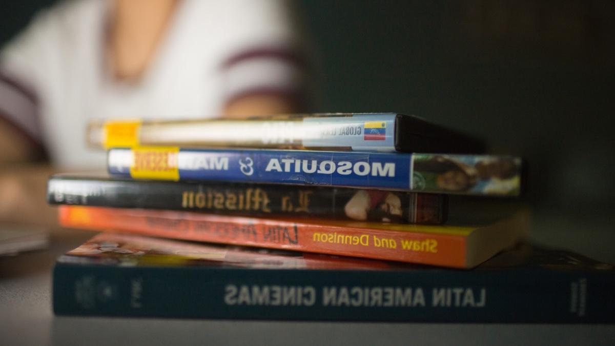 Stack of 西班牙语 books on a table with student in the background 