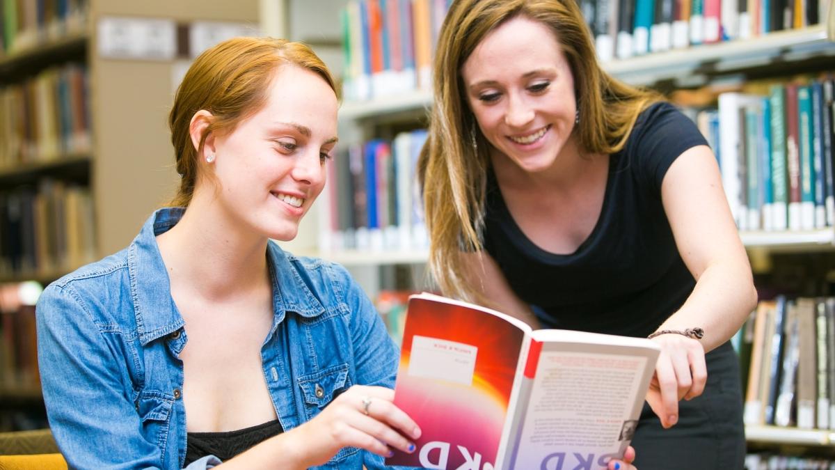 Two students discussing a book.