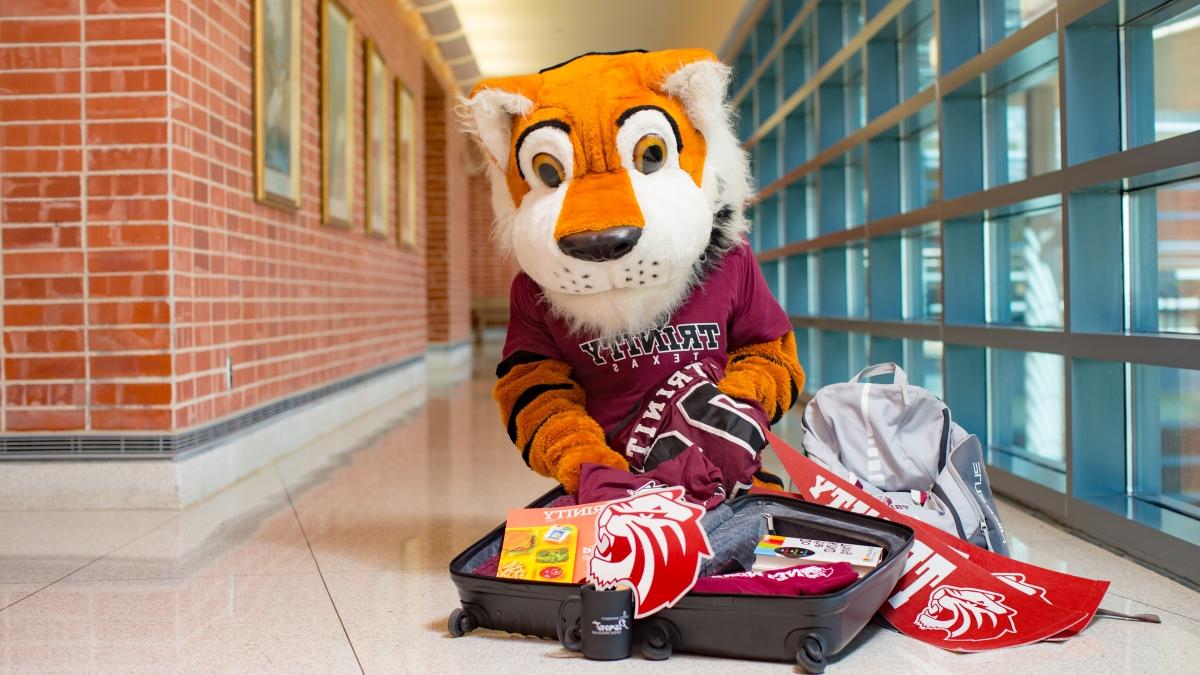 the LeeRoy Tiger mascot poses with an open suitcase full of 赌博娱乐平台网址大全 swag